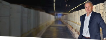 Martin Liebl v obleku stojí ve skladu s cihlami